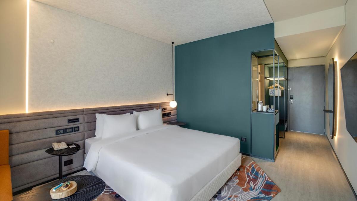 a bedroom with a white bed and a blue wall at Novotel Pune Viman Nagar Road in Pune