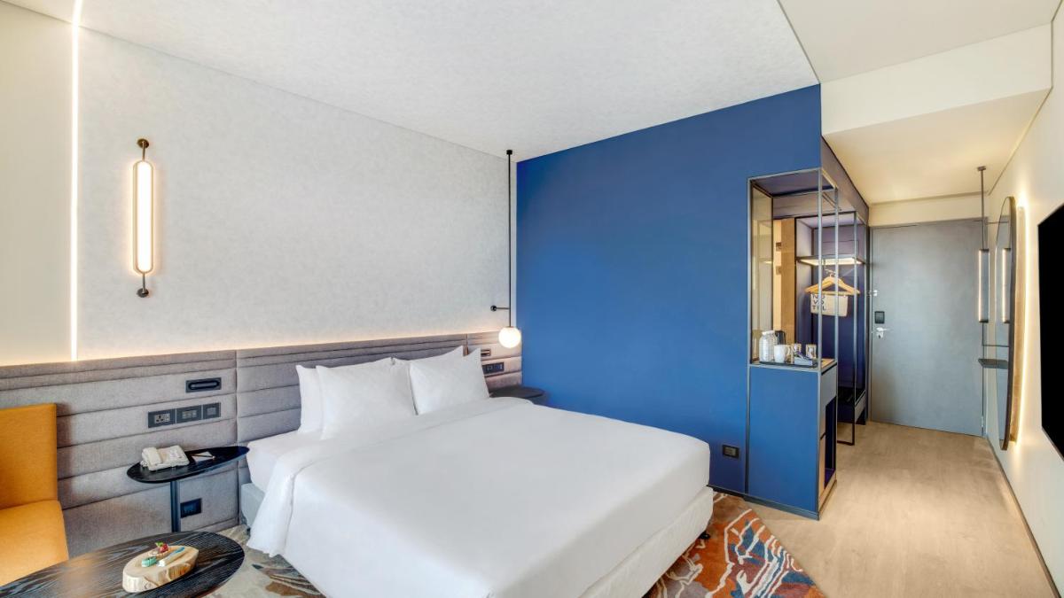 a bedroom with a white bed and a blue wall at Novotel Pune Viman Nagar Road in Pune