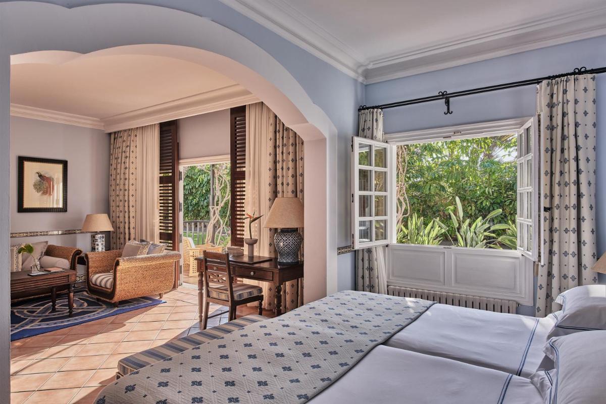 Un dormitorio con una cama y un escritorio y una ventana. en Seaside Grand Hotel Residencia - Gran Lujo, en Maspalomas
