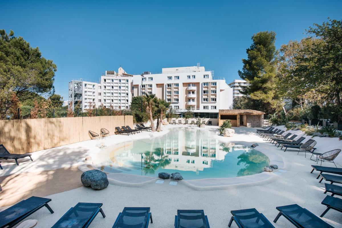 une piscine avec des chaises longues et un bâtiment en arrière-plan dans l'établissement Le Drip's, à Marseille