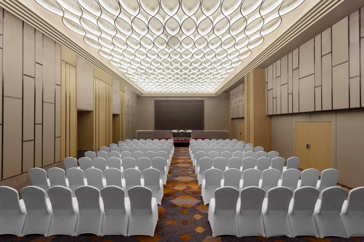 an empty room with white chairs and a projection screen at Courtyard by Marriott Amritsar in Amritsar