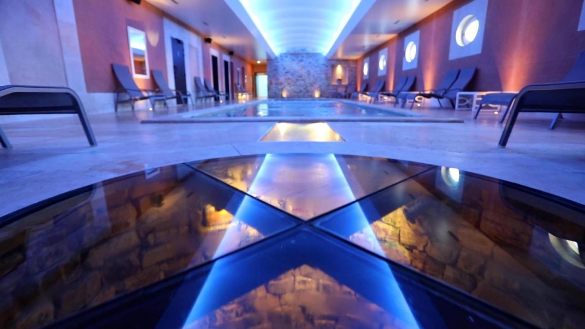 un hall d'entrée avec une grande piscine d'eau dans un bâtiment dans l'établissement Auberge de Cassagne & Spa, au Pontet