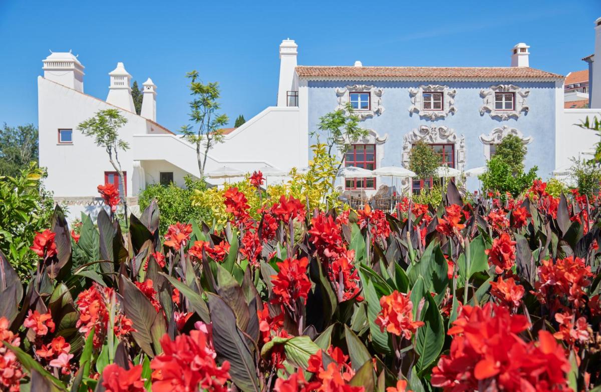 um jardim de flores vermelhas em frente a um edifício branco em Vermelho Melides - Relais & Châteaux em Melides