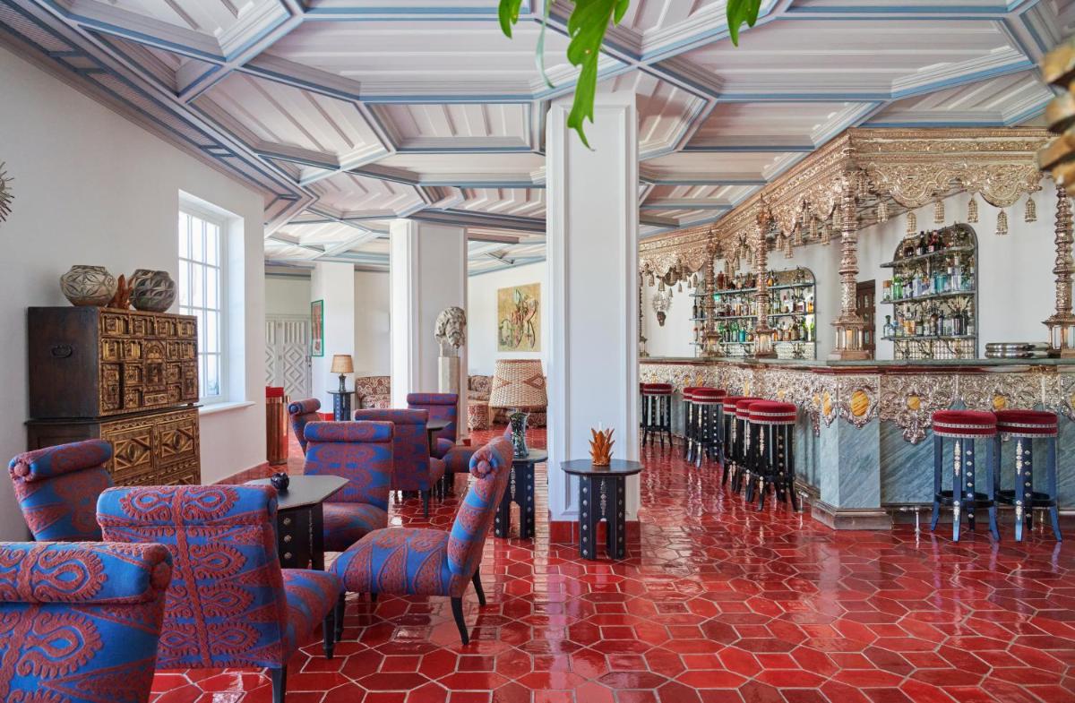 um átrio com um bar com cadeiras azuis e um piso vermelho em Vermelho Melides - Relais & Châteaux em Melides
