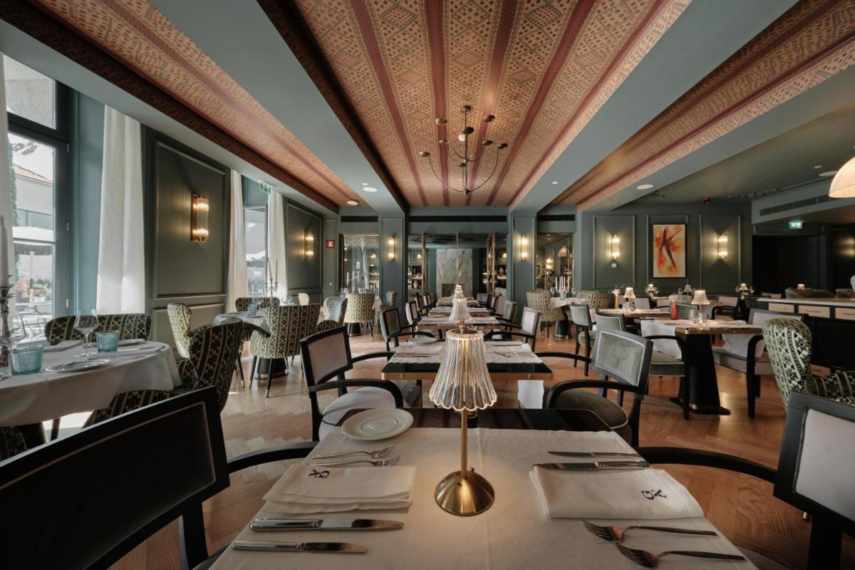 um restaurante com mesas e cadeiras e um teto em GA Palace Hotel & Spa, a XIXth-Century Villa no Porto
