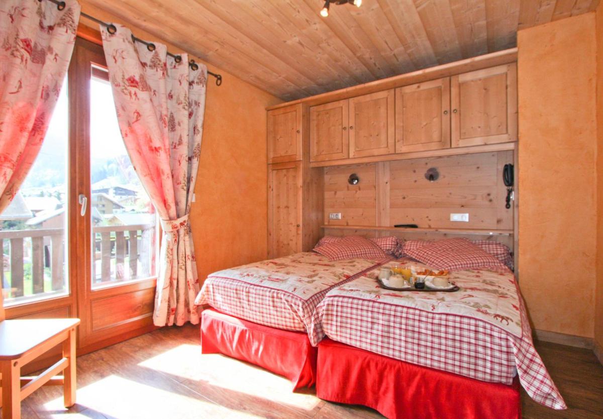 une chambre avec un lit et une grande fenêtre dans l'établissement Alpen Roc, à Morzine