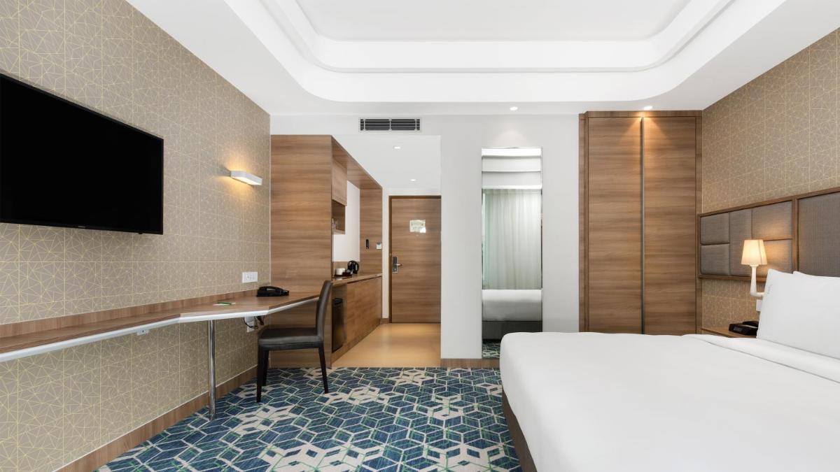 a hotel room with a bed and a desk and a television at Holiday Inn Gurugram Sector 90 by IHG in Gurgaon