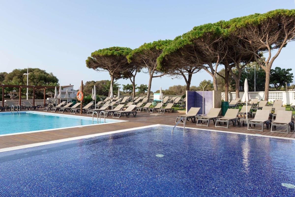 una piscina con tumbonas y sillas en Alua Illa de Menorca, en S'Algar