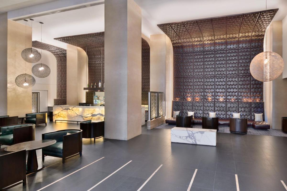 a lobby of a hotel with tables and chairs at The Westin Hyderabad Mindspace in Hyderabad