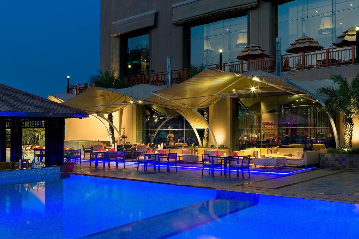 a hotel with a pool with tables and chairs at The Westin Hyderabad Mindspace in Hyderabad