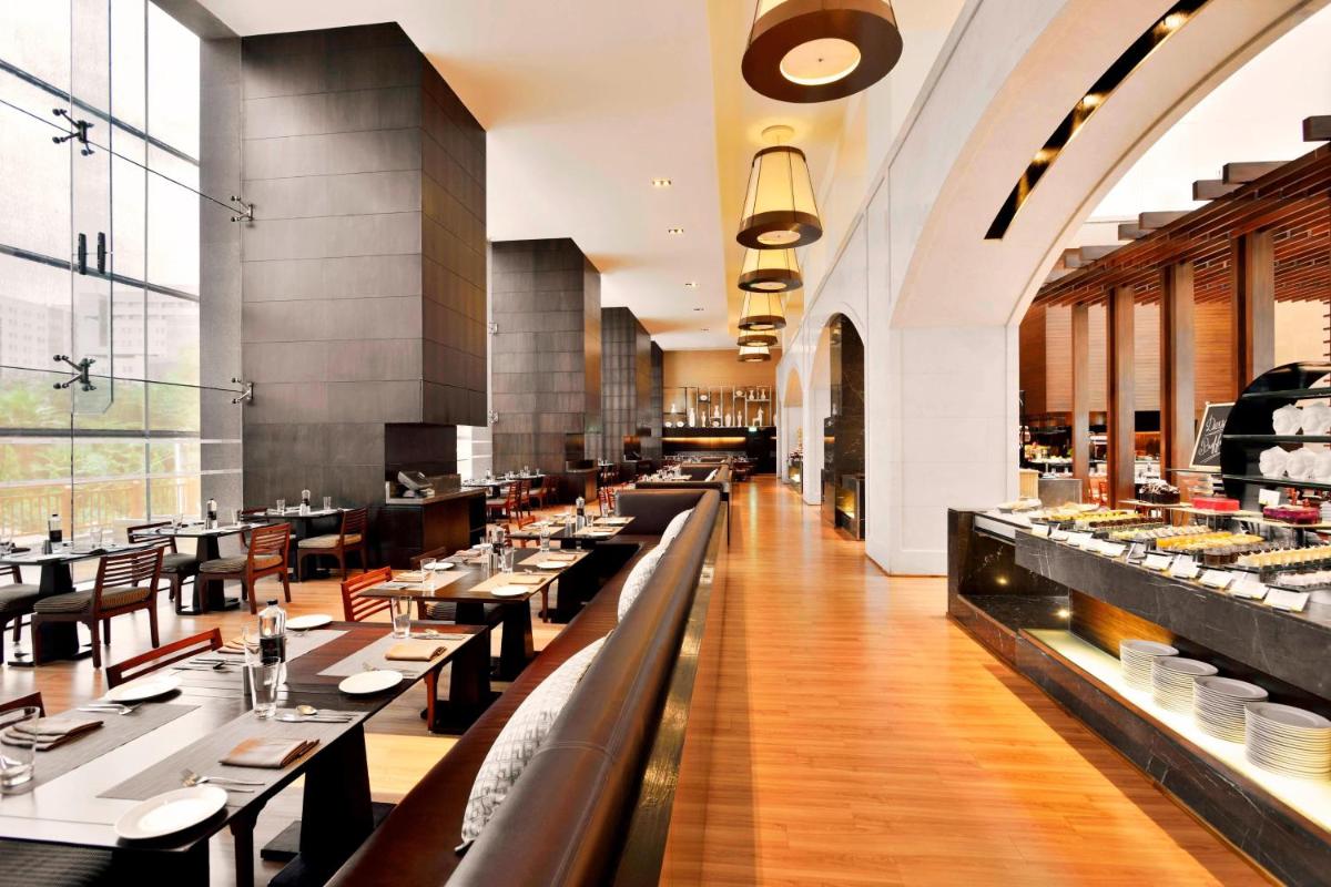 a dining room with tables and chairs in a restaurant at The Westin Hyderabad Mindspace in Hyderabad