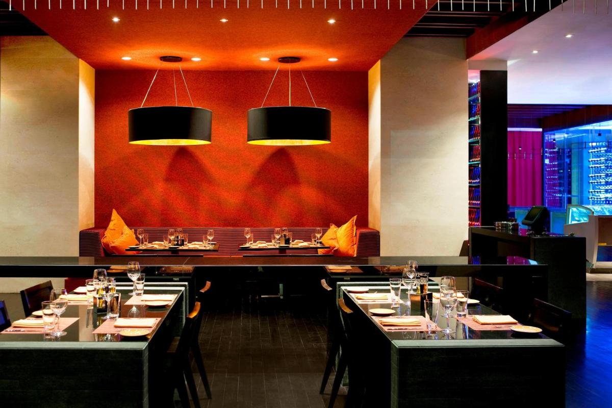 a dining room with tables and chairs and lights at The Westin Hyderabad Mindspace in Hyderabad