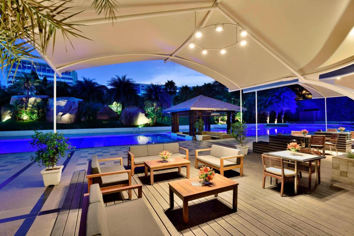 a patio with tables and chairs and a pool at The Westin Hyderabad Mindspace in Hyderabad