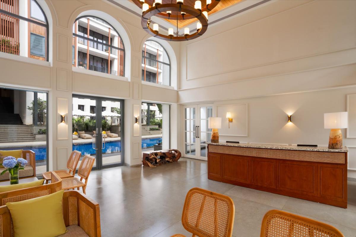 a large lobby with a reception desk and chairs at The Astor - All Suites Hotel Candolim Goa in Candolim a large lobby with a reception desk and chairs at The Astor - All Suites Hotel Candolim Goa in Candolim