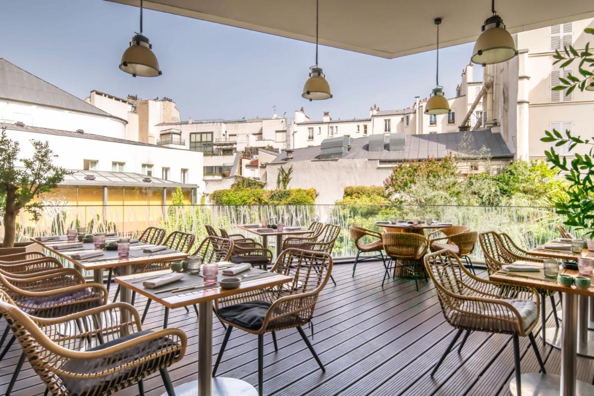 un restaurant avec des tables et des chaises sur une terrasse dans l'établissement Renaissance Paris Arc de Triomphe Hotel, à Paris
