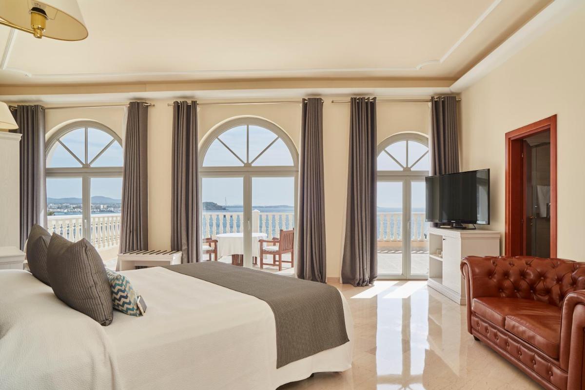 Un dormitorio con una cama y un sofá y ventanas. en Grand Hotel Palladium Santa Eulalia del Río, en Santa Eulària des Riu