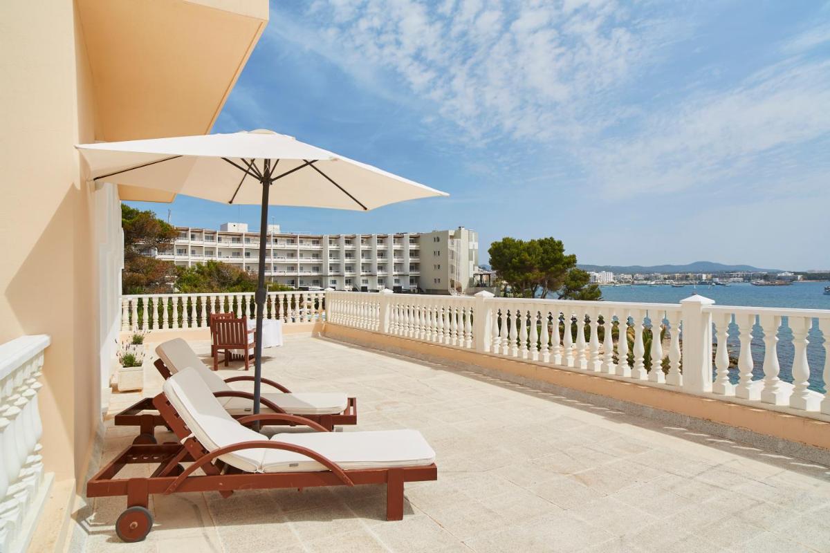 un patio con sillas y una sombrilla en el balcón en Grand Hotel Palladium Santa Eulalia del Río, en Santa Eulària des Riu