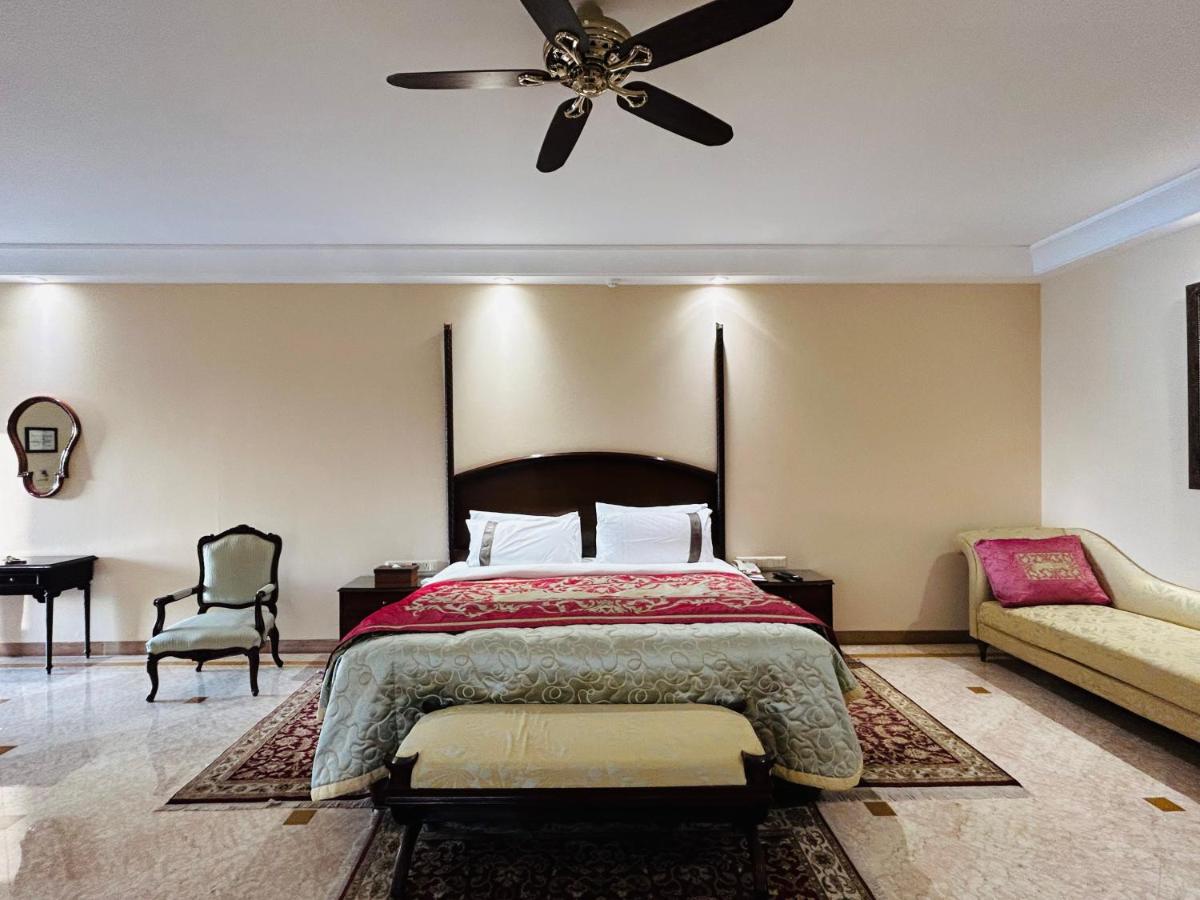 a bedroom with a bed and a ceiling fan at The Lalit Laxmi Vilas Palace in Udaipur