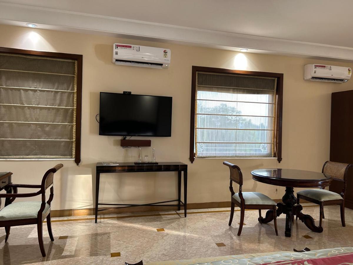 a living room with a table and a flat screen tv at The Lalit Laxmi Vilas Palace in Udaipur