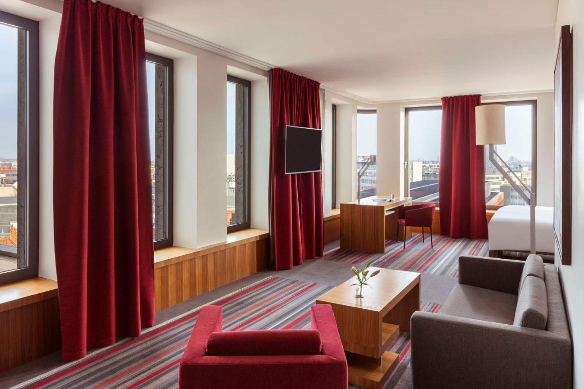 ein Hotelzimmer mit roten Vorhängen und einem Schlafzimmer in der Unterkunft Dorint Kurfürstendamm Berlin in Berlin ein Hotelzimmer mit roten Vorhängen und einem Schlafzimmer in der Unterkunft Dorint Kurfürstendamm Berlin in Berlin