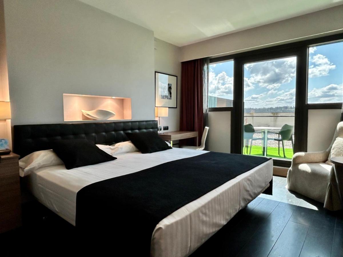 Un dormitorio con una cama grande y una ventana grande. en URH Hotel Spa Zen Balagares, en Overo