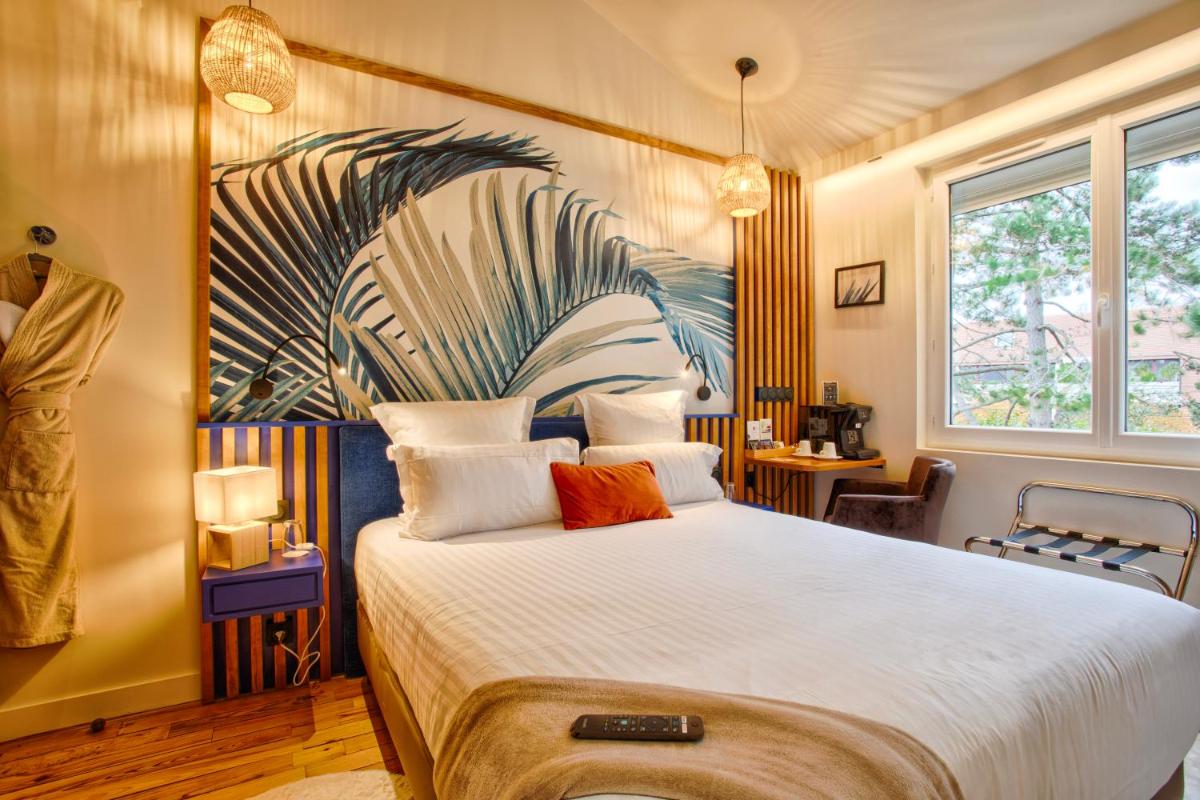 une chambre avec un grand lit avec un tableau au mur dans l'établissement Le Castel Cabourg hôtel & SPA- Restaurant La Calypso, à Cabourg