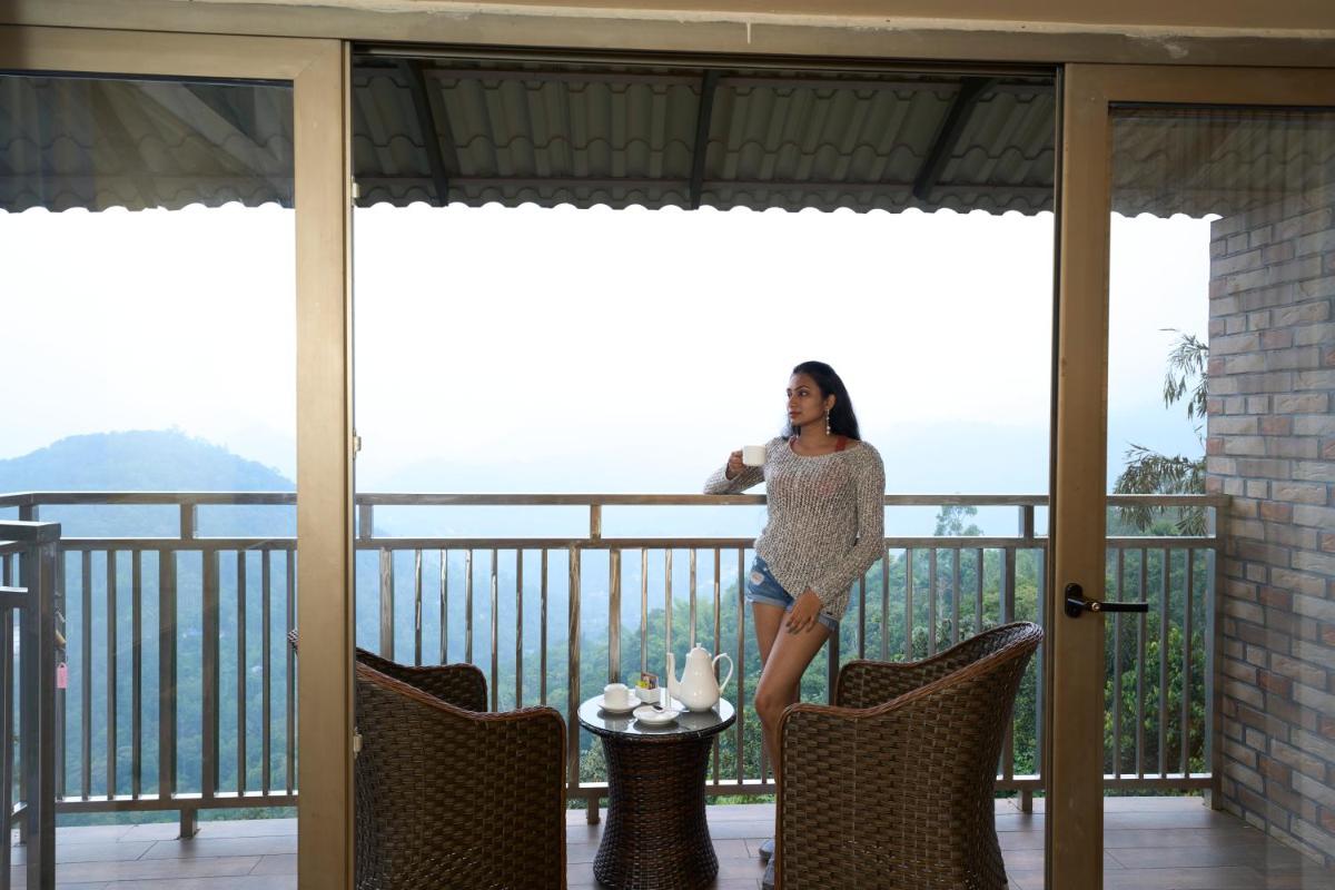 a woman standing on the balcony of a house at Elephant Passage in Munnar