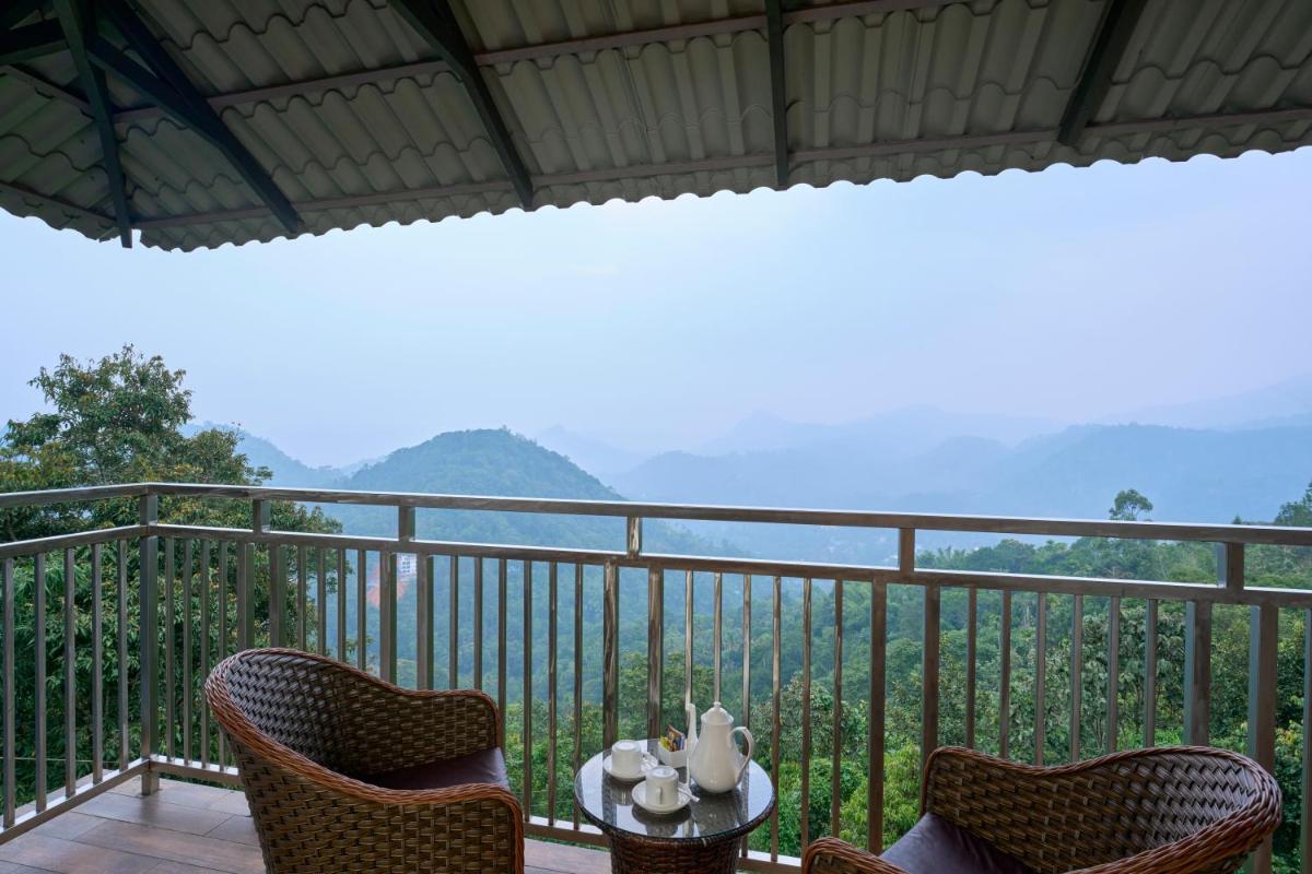 a balcony with chairs and a table with a view at Elephant Passage in Munnar