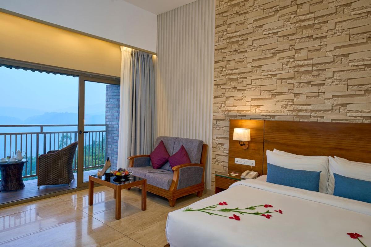 a hotel room with a bed and a chair and a balcony at Elephant Passage in Munnar
