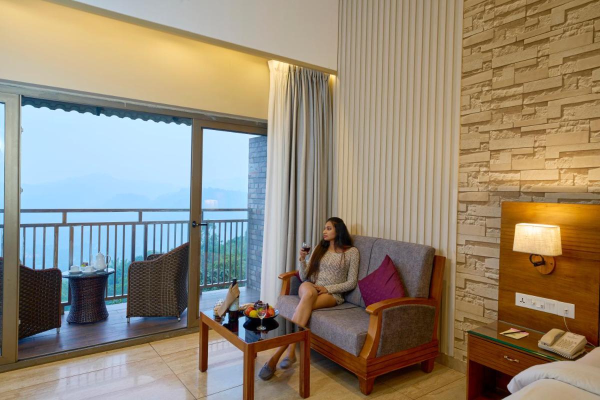 a woman sitting on a chair in a room with a balcony at Elephant Passage in Munnar