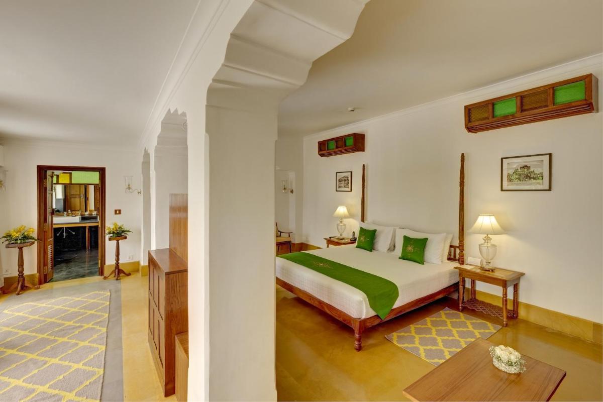 a bedroom with a bed with green pillows at Saraca Hotel Lucknow in Lucknow