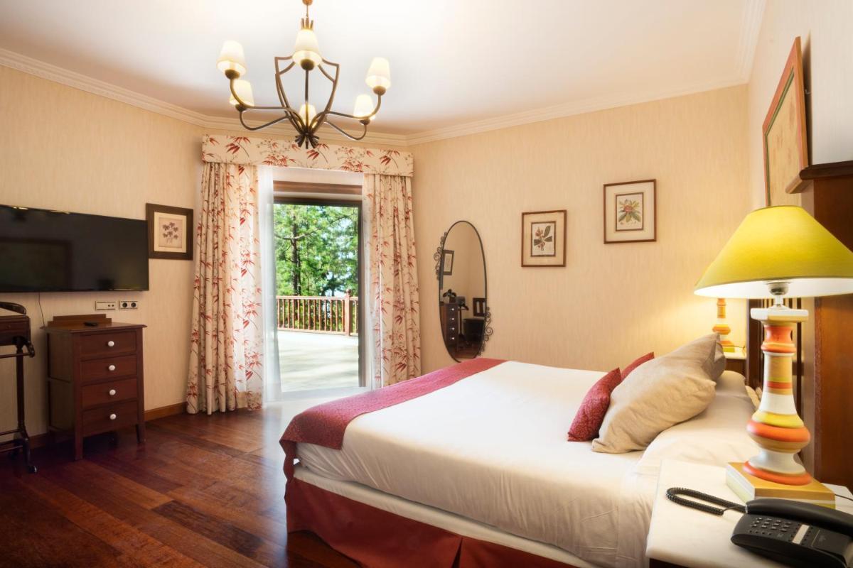 Un dormitorio con una cama y un televisor y una ventana. en Hotel Spa Villalba, en Vilaflor