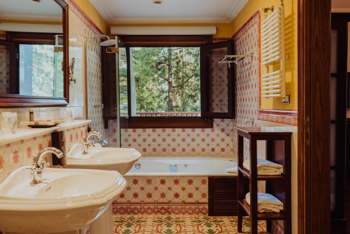 Un baño con dos lavabos y una bañera y una ventana. en Hotel Spa Villalba, en Vilaflor