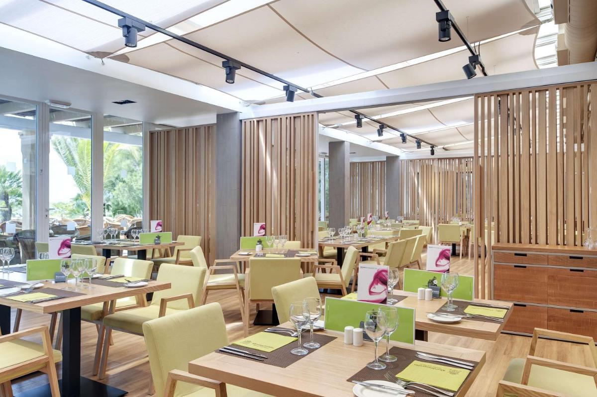 un restaurante con mesas de madera y sillas amarillas en Barceló Jerez Montecastillo & Convention Center, en Jerez de la Frontera