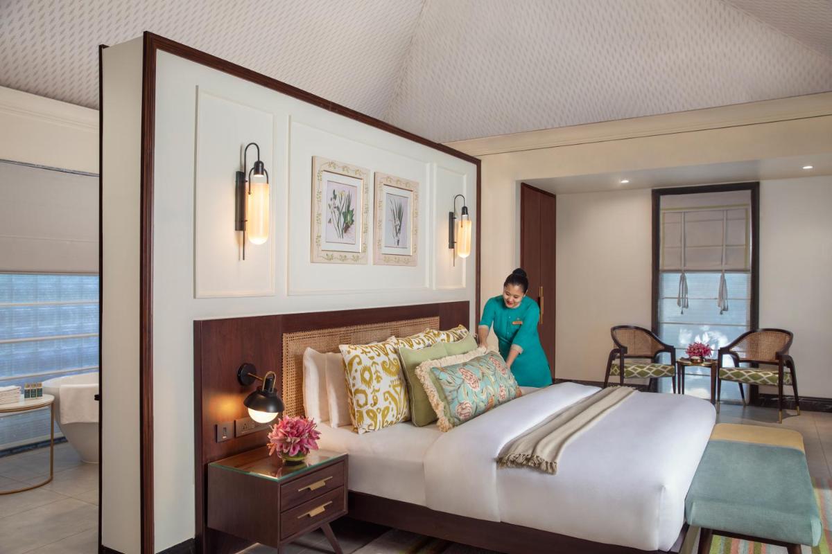 a woman standing in a bedroom with a large bed at Anand Kashi by the Ganges Rishikesh - IHCL Seleqtions in Rishīkesh