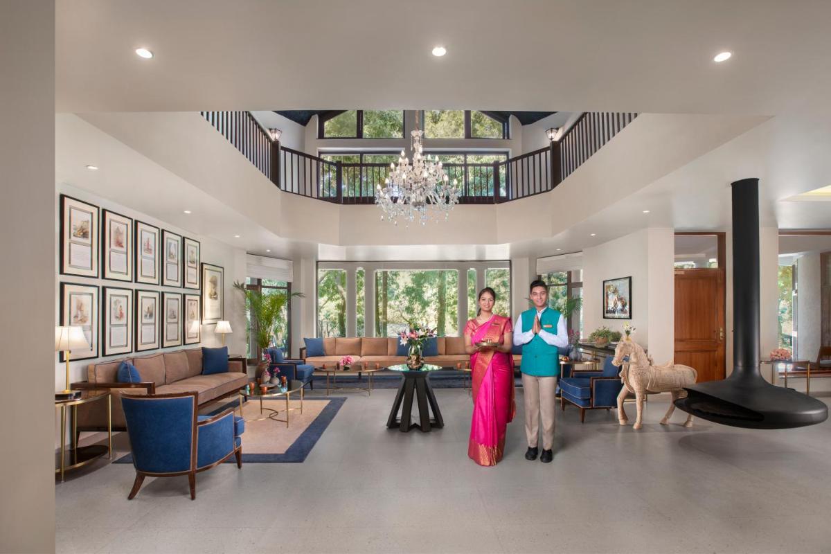 two people are standing in a living room at Anand Kashi by the Ganges Rishikesh - IHCL Seleqtions in Rishīkesh