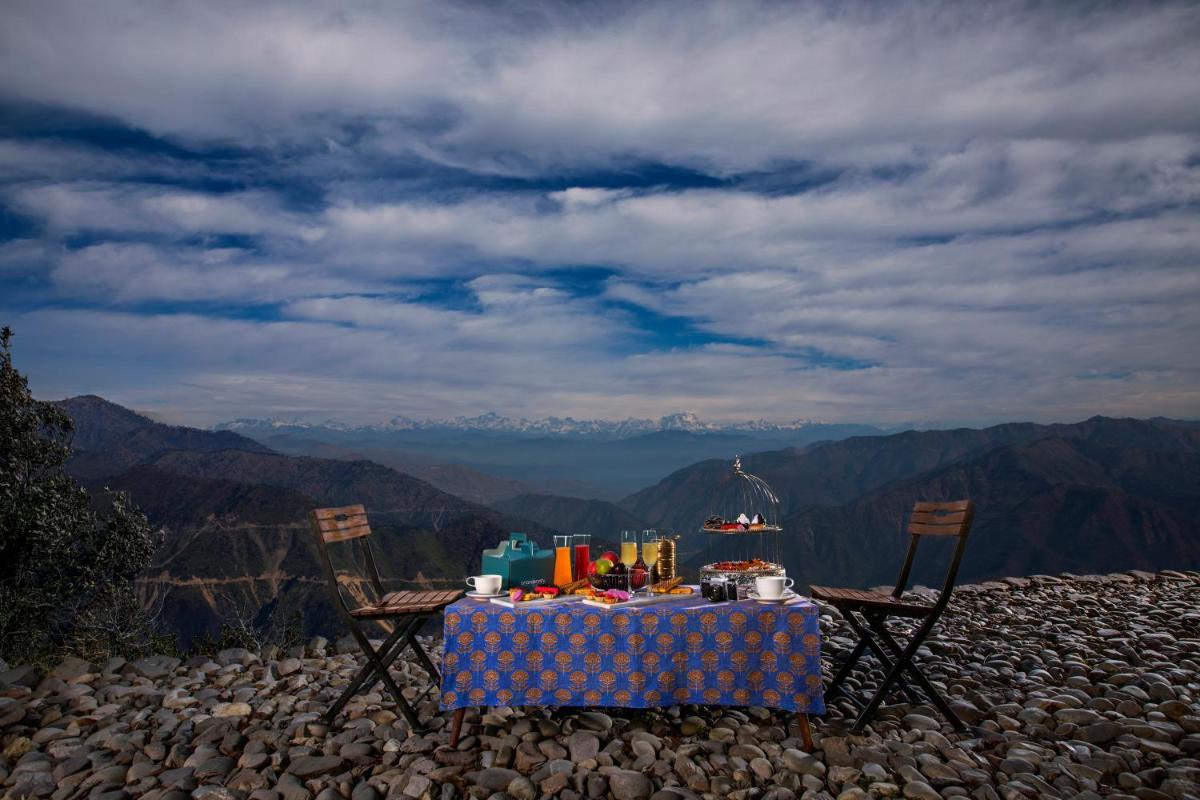 a table and chairs on top of a mountain at Anand Kashi by the Ganges Rishikesh - IHCL Seleqtions in Rishīkesh