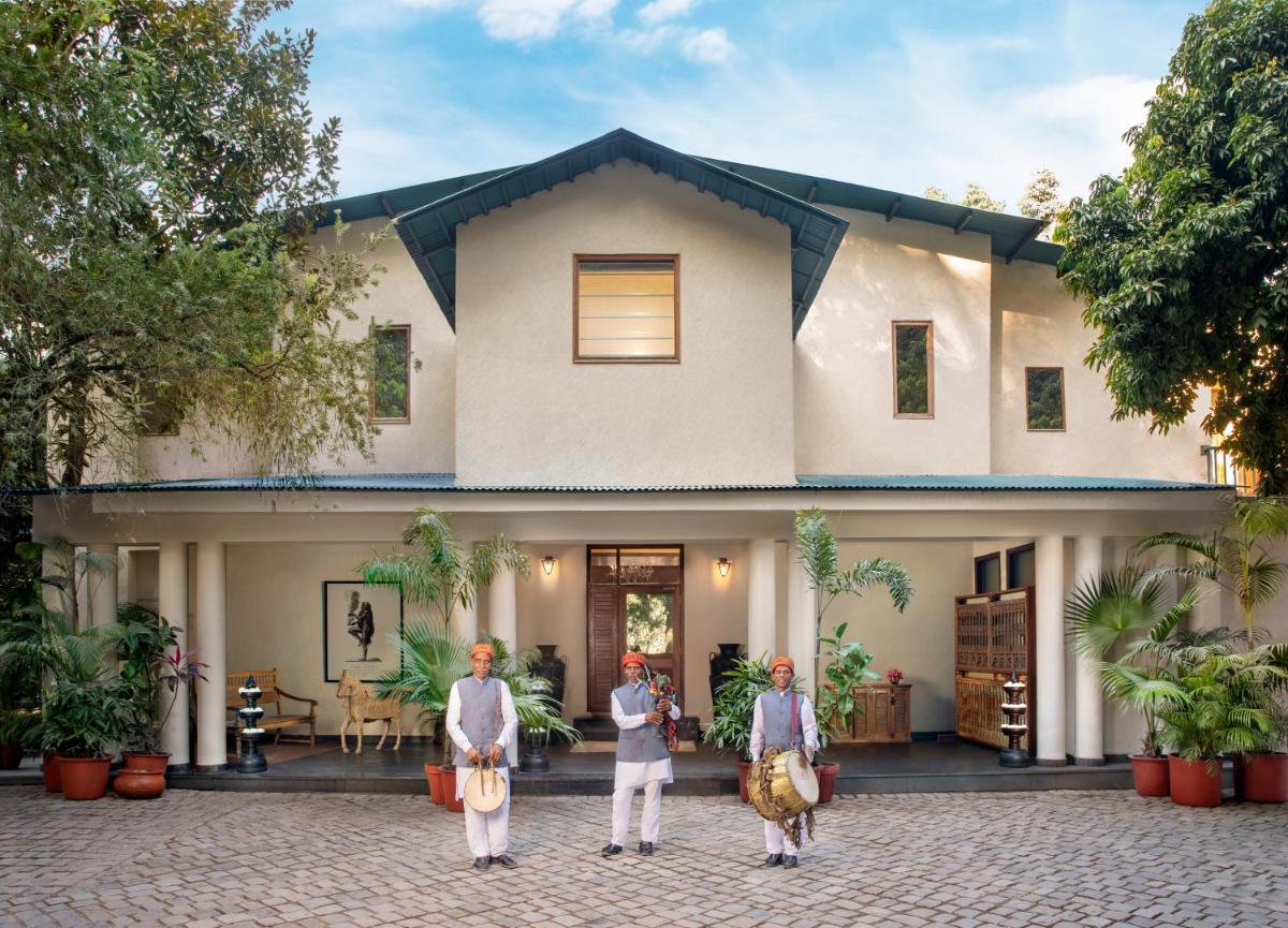 three people standing in front of a house at Anand Kashi by the Ganges Rishikesh - IHCL Seleqtions in Rishīkesh