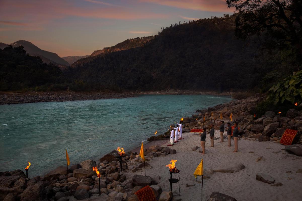 a group of people standing on a beach next to a river at Anand Kashi by the Ganges Rishikesh - IHCL Seleqtions in Rishīkesh