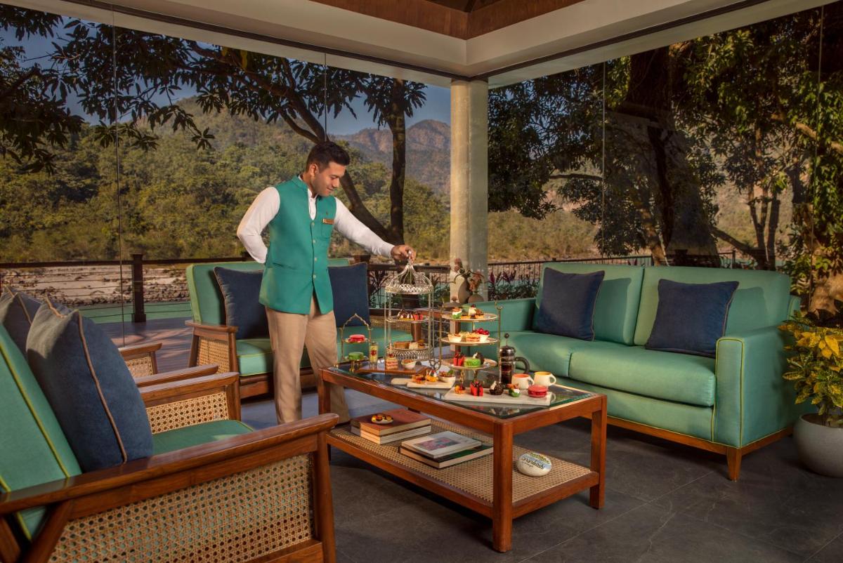 a man standing in a living room with a table at Anand Kashi by the Ganges Rishikesh - IHCL Seleqtions in Rishīkesh