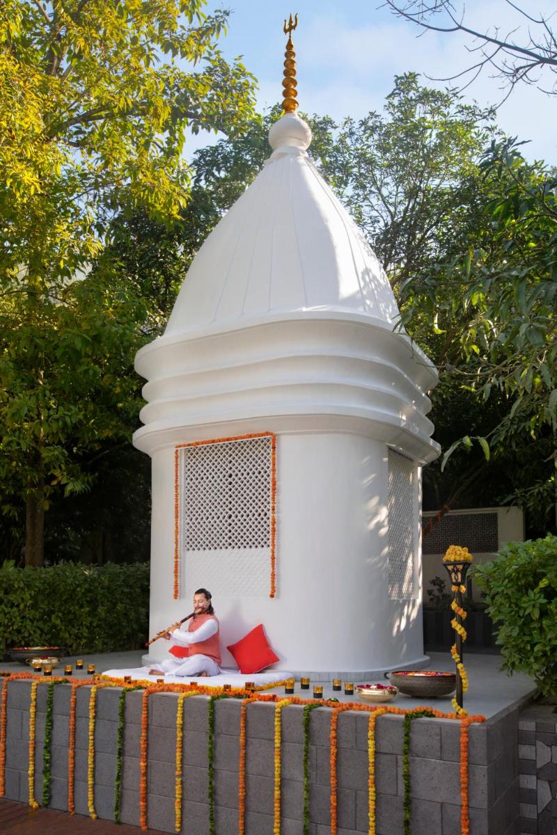 a woman sitting in front of a white temple at Anand Kashi by the Ganges Rishikesh - IHCL Seleqtions in Rishīkesh