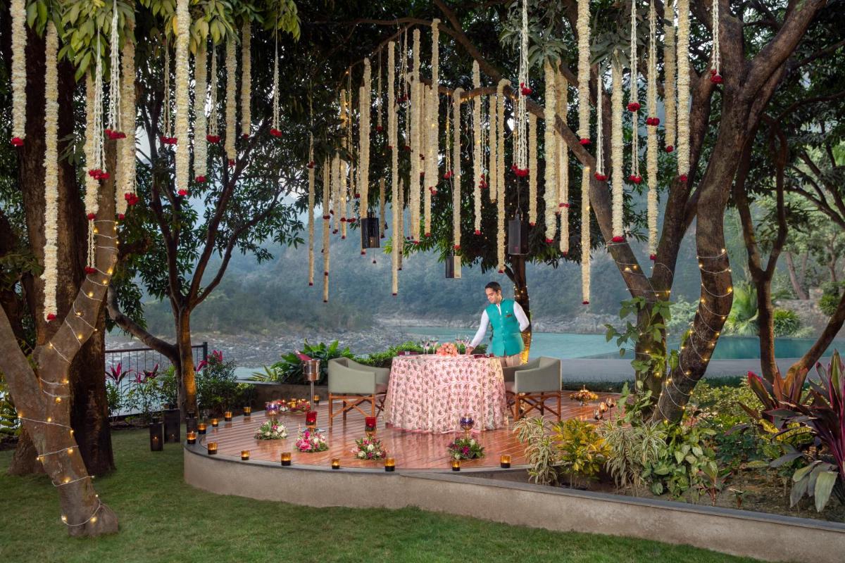 a woman standing at a table in a garden at Anand Kashi by the Ganges Rishikesh - IHCL Seleqtions in Rishīkesh