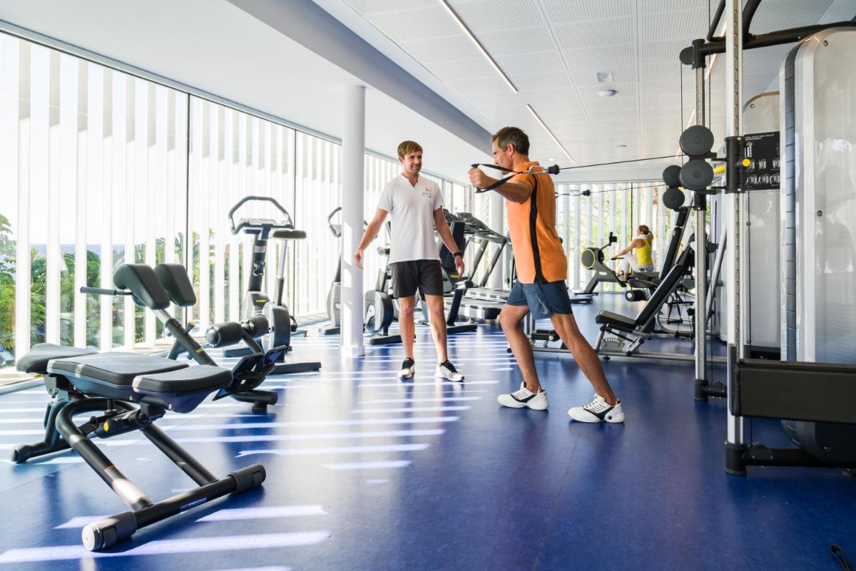 dos hombres parados en un gimnasio mirando su reloj en OCEANO Health Spa Hotel, en Punta del Hidalgo