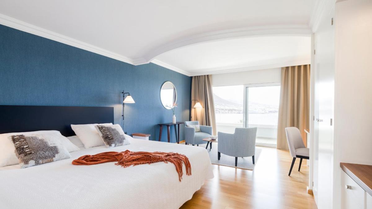 Un dormitorio con una gran cama blanca y una pared azul. en OCEANO Health Spa Hotel, en Punta del Hidalgo 17 fotos más