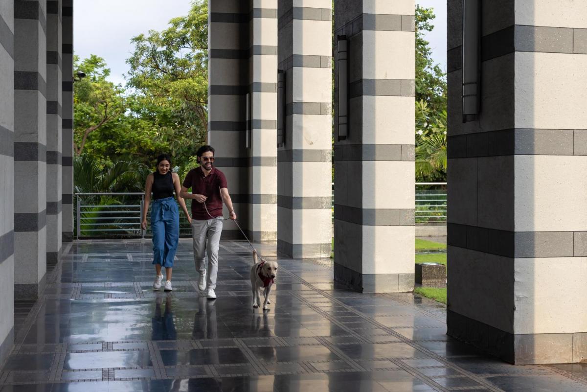 a man and a woman walking a dog in a building at Grand Hyatt Mumbai Hotel and Residences in Mumbai