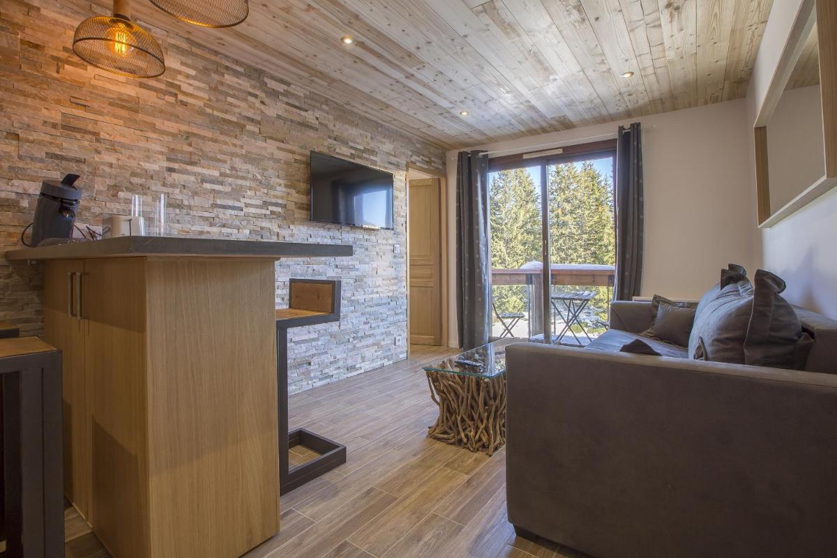 un salon avec un canapé et un mur en pierre dans l'établissement Résidence Le Domaine du Jardin Alpin - Courchevel 1850, à Courchevel