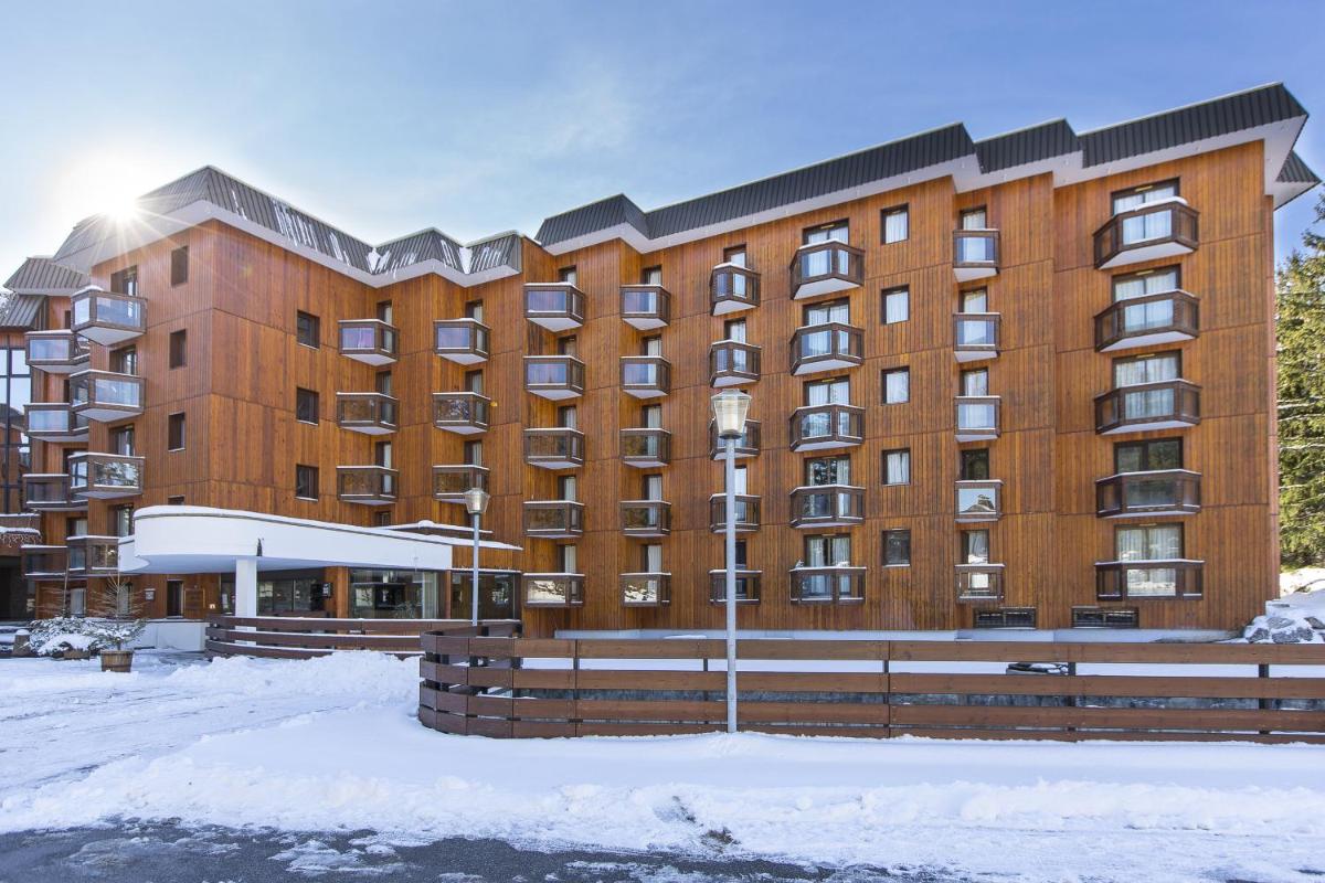 un grand bâtiment avec de la neige devant lui dans l'établissement Résidence Le Domaine du Jardin Alpin - Courchevel 1850, à Courchevel
