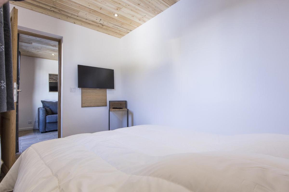 une chambre avec un lit blanc et une télévision à écran plat dans l'établissement Résidence Le Domaine du Jardin Alpin - Courchevel 1850, à Courchevel 37 autres photos
