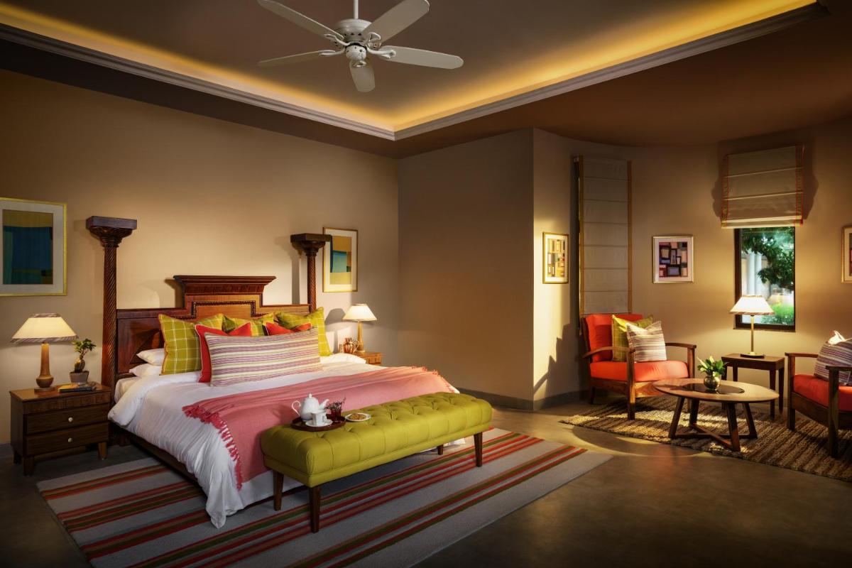 a bedroom with a king sized bed and a couch at Anand Kashi by the Ganges Rishikesh - IHCL Seleqtions in Rishīkesh
