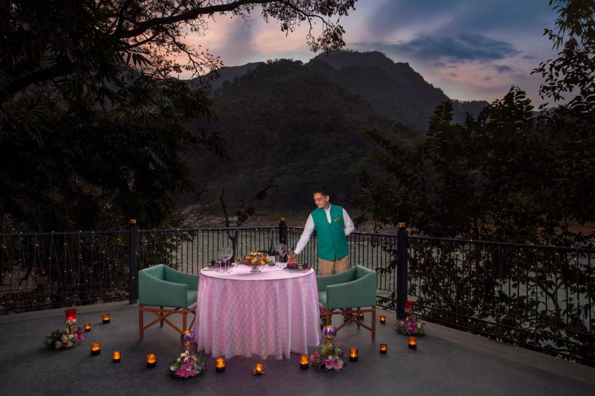 a man in an apron standing next to a table at Anand Kashi by the Ganges Rishikesh - IHCL Seleqtions in Rishīkesh